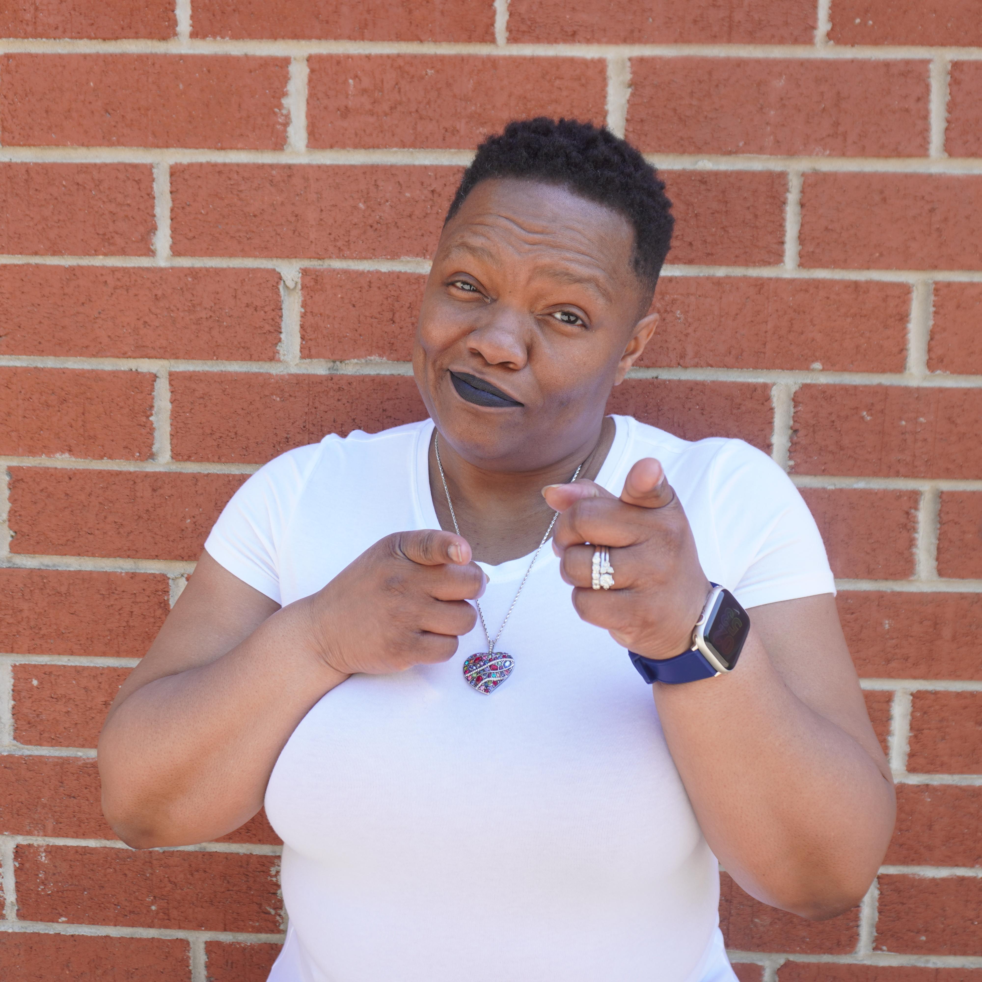 Tia A. Williams, Principal Systems-Thinking Architect and creator of The Inbound Authority System™, pointing directly at the viewer against a brick wall background.