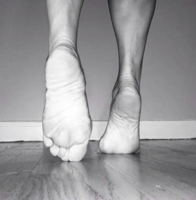 Black-and-white photograph of Balance Yoga owner Angie Ryan’s feet while walking, showing the sole of one foot and the weight-bearing heel of the other.