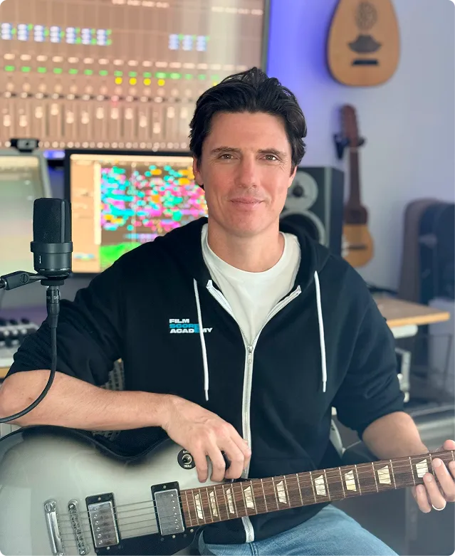 Film composer at professional recording console with sound engineer in recording studio