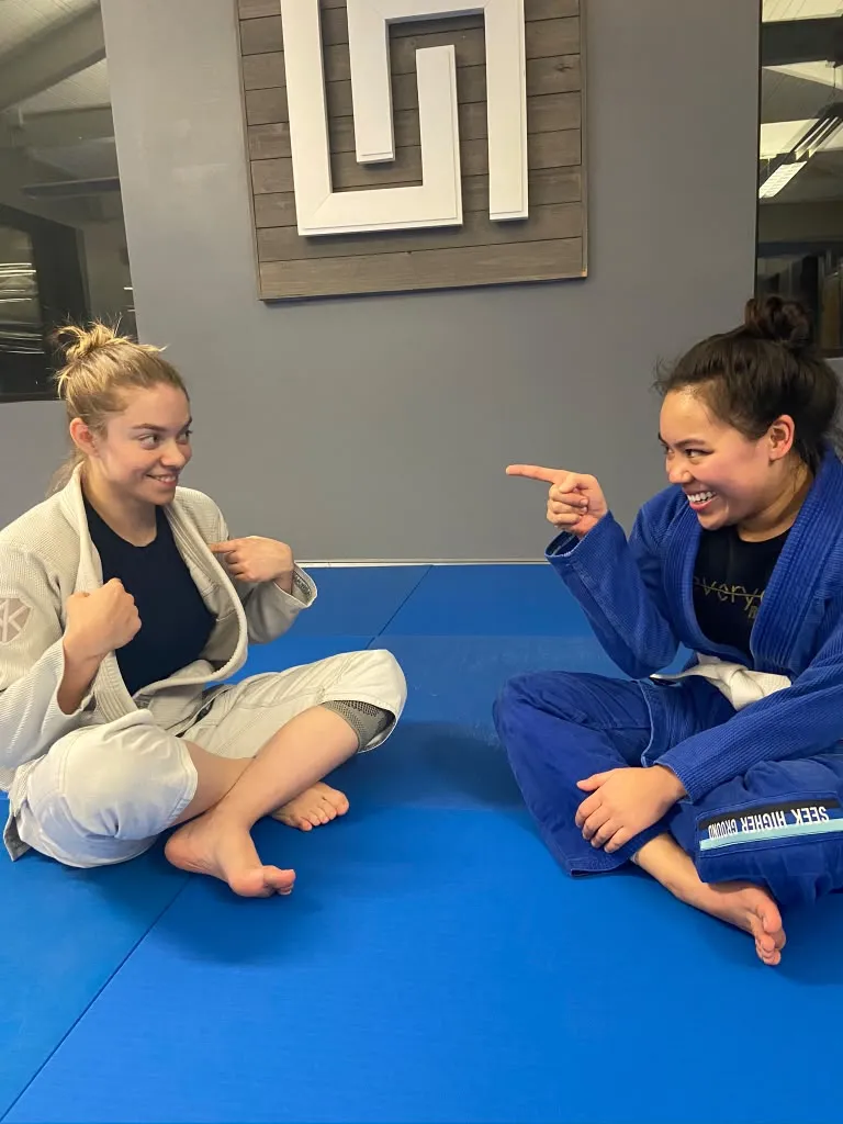 two female athletes smiling while on the mats