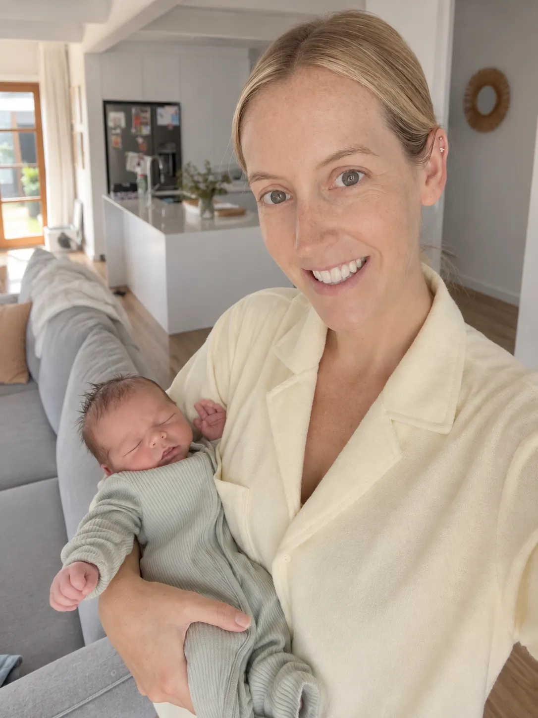 Elly from Baby Sleep Collective holding a sleeping newborn during an in-home visit.