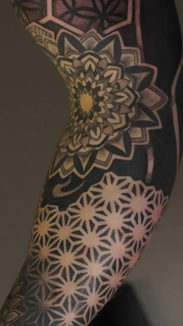 Ornamental mandala on upper back, top-down photographic composition showing symmetry and negative space, warm studio lighting, intricate dotwork and geometric repetition in high-resolution detail.