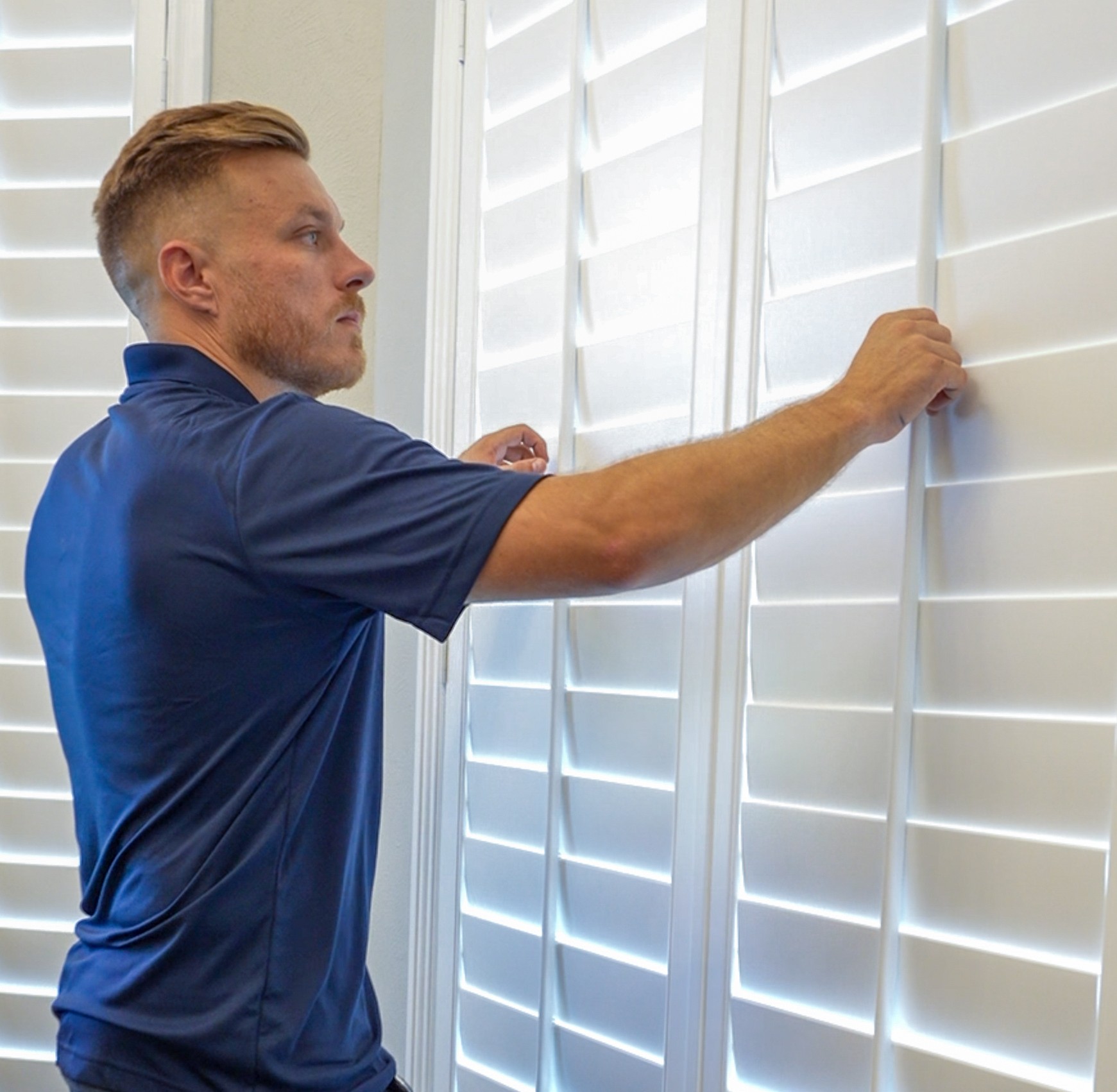 Professional installer adjusting custom white plantation shutters