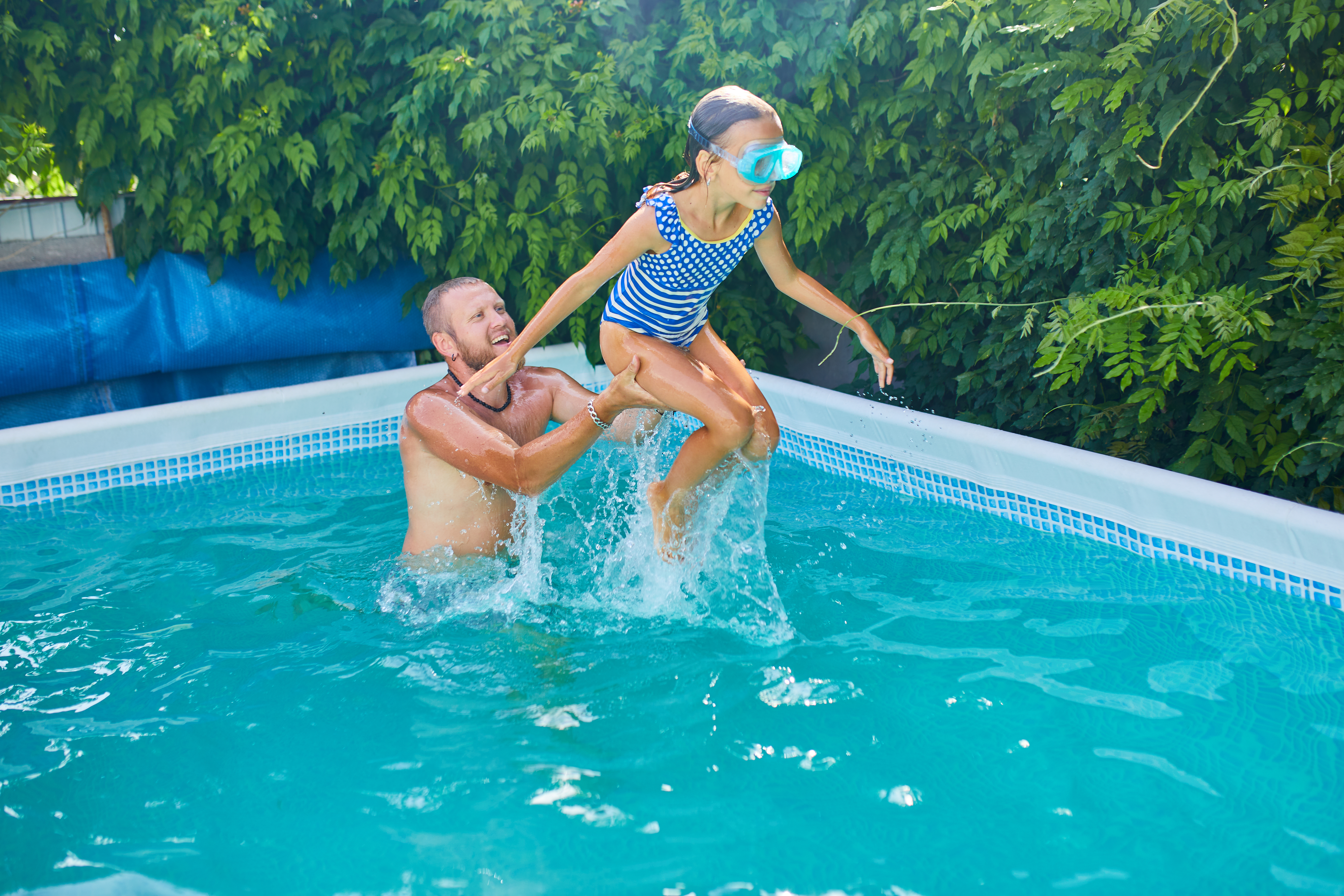 man plays with kid in above ground pool