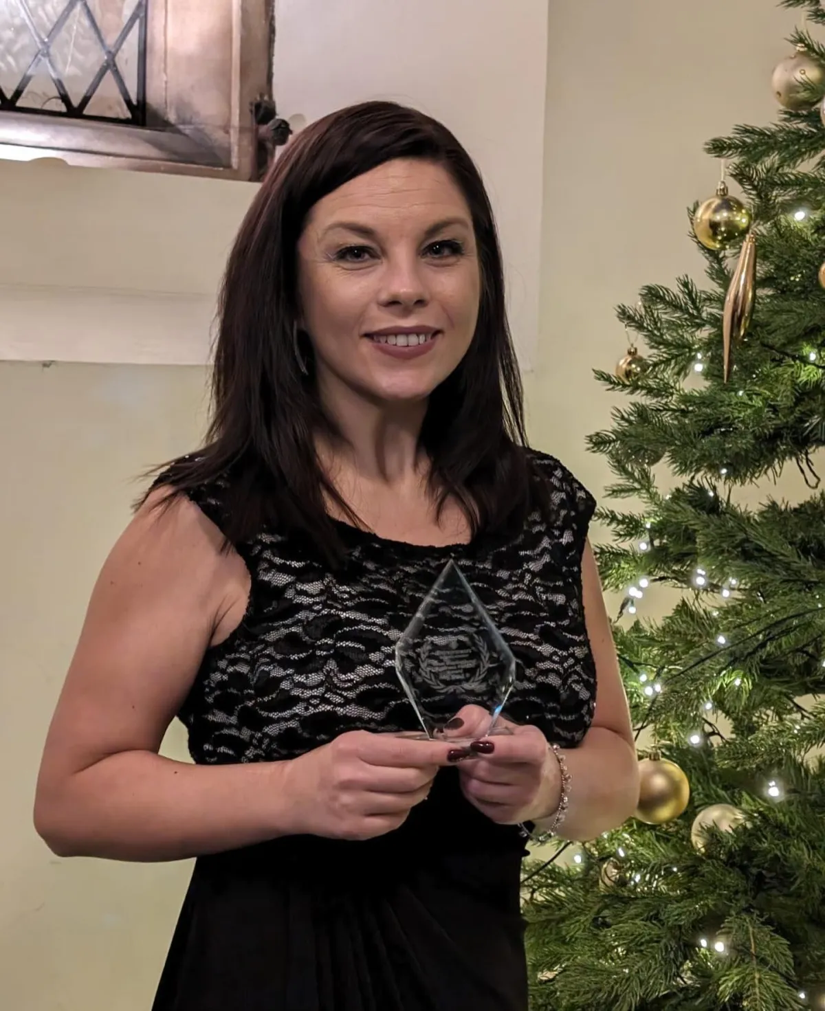 Michelle Rowlinson in a smart black dress, smiling, in a relaxed setting