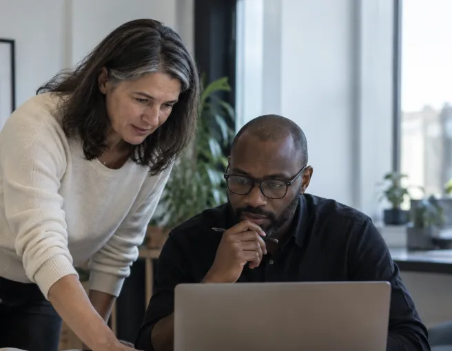 Professional woman guiding a colleague through new workplace policies, highlighting the importance of menopause-related adjustments as required by evolving legislation in the UK and globally.