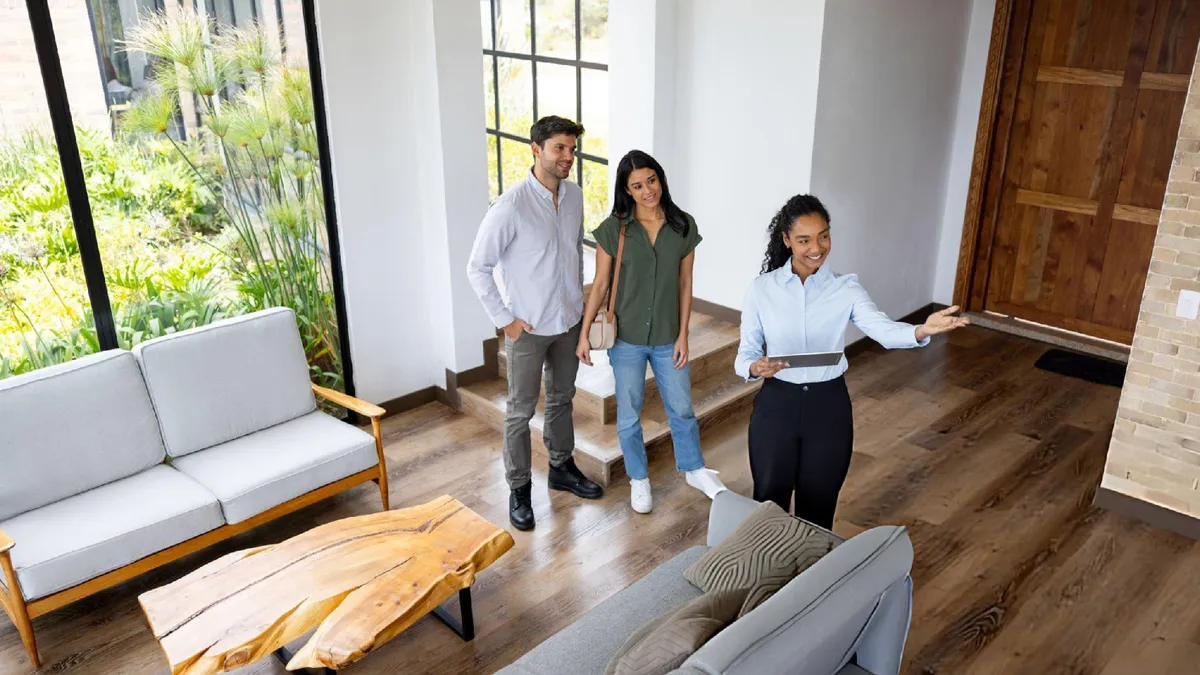 Real estate agent gives a couple a tour of a bright modern home interior during viewing.