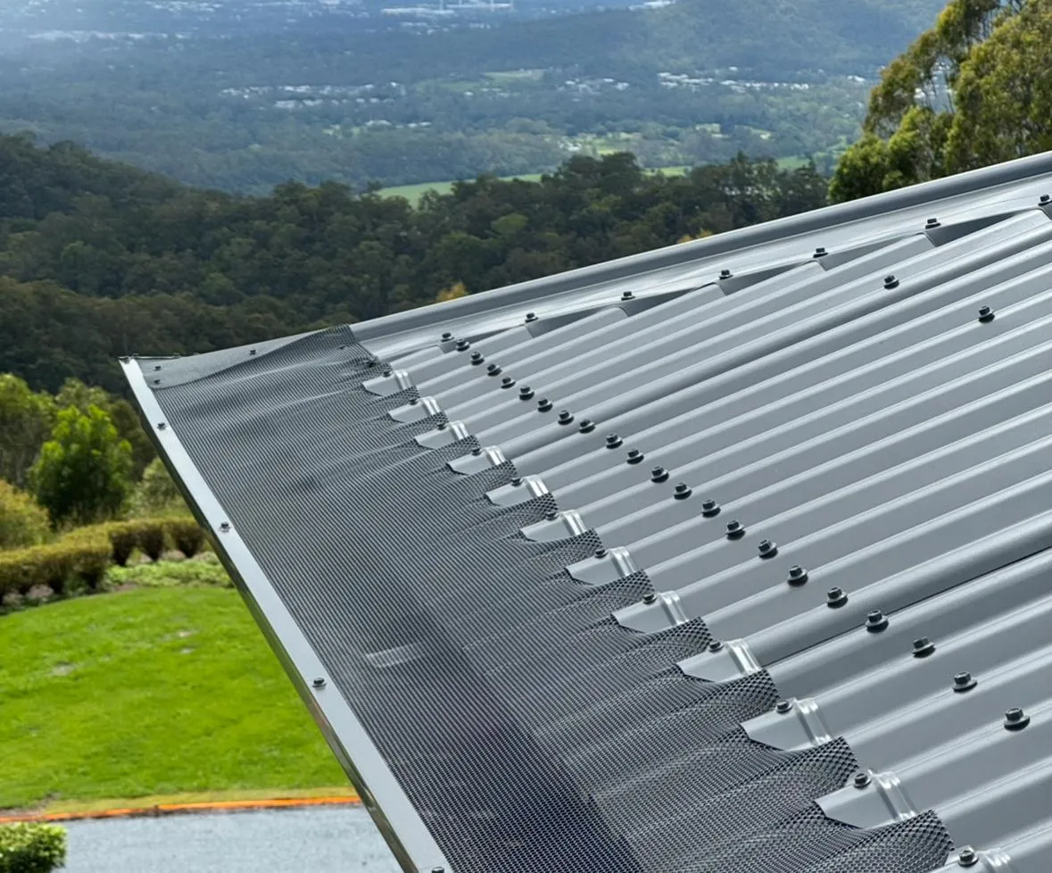 Professional gutter guard installation on a modern corrugated roof with aluminium mesh, protecting gutters from leaves and debris in Queensland.