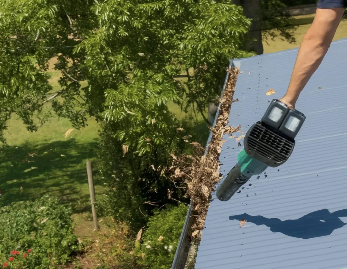 Team member removing leaves from gutter before gutter guard installation