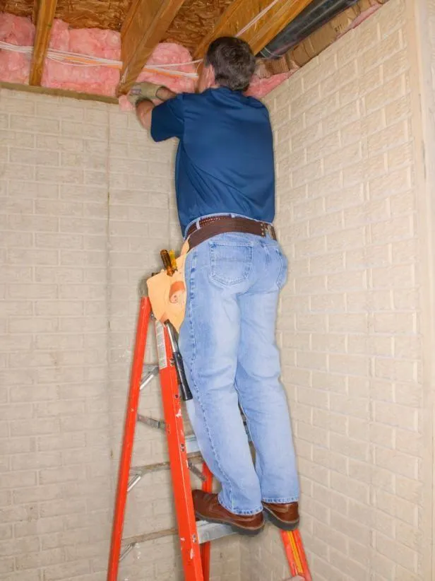 a person on a ladder installing foam