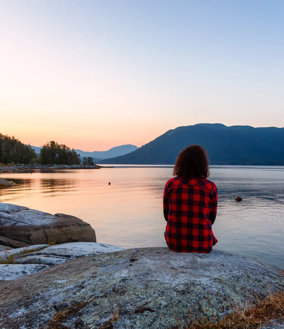 Women sitting at a lake, overlooking the unset