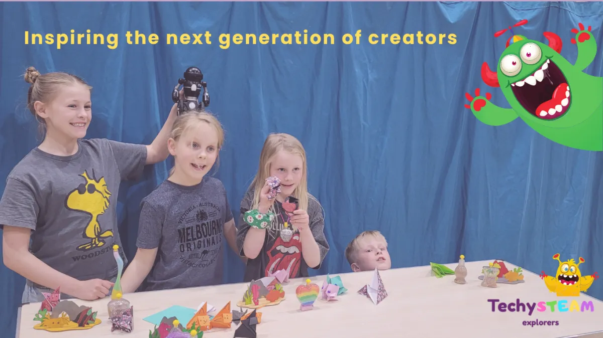 Primary-aged children proudly showing their STEAM projects and a small robot during a hands-on school workshop.