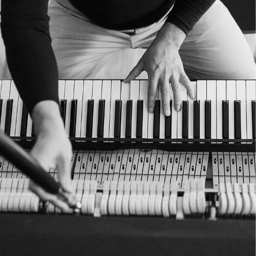 Close up of Brian's hands on piano keys, tuning a piano in Grand Rapids, Michigan.