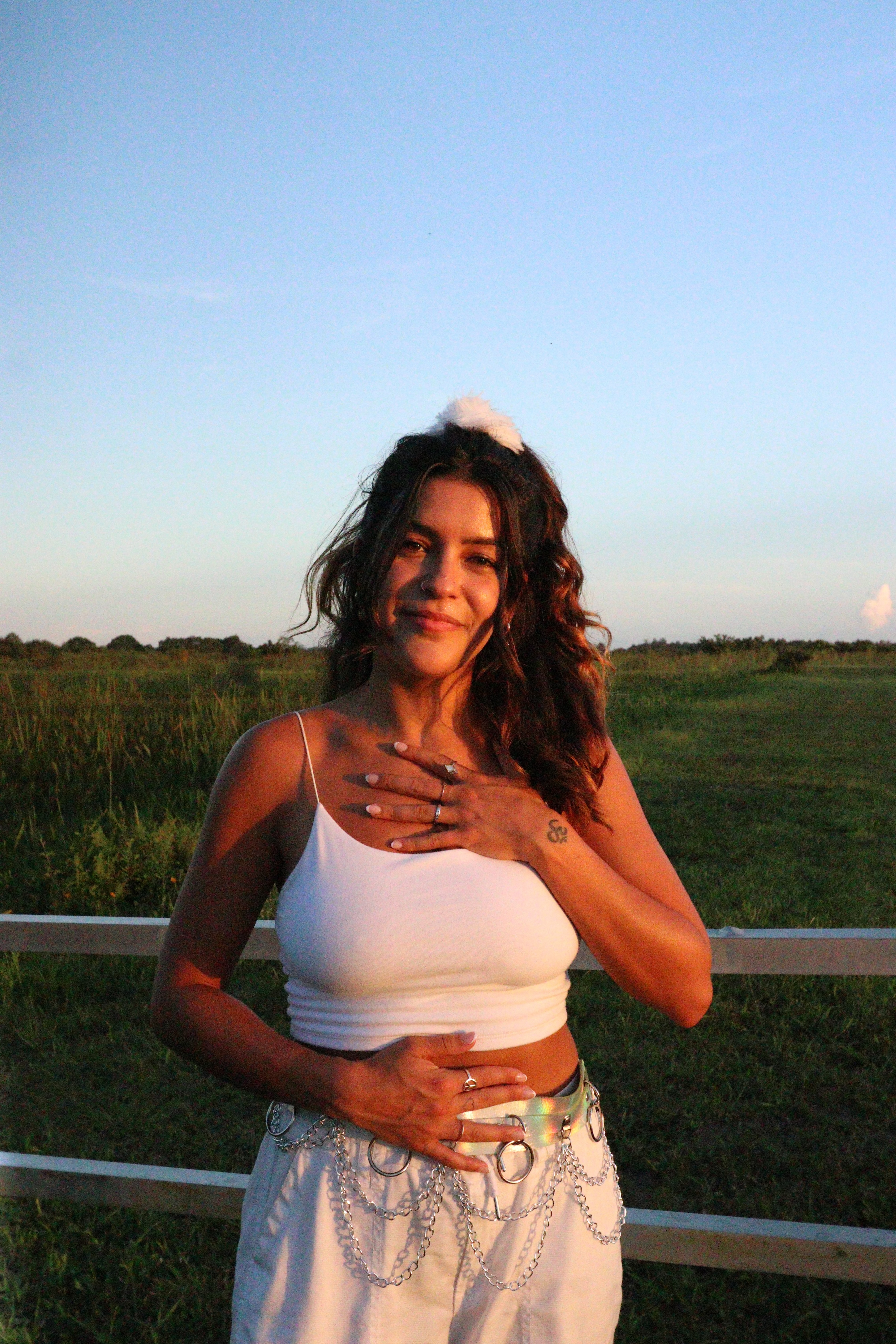 Portrait of Madi, hand on heart, in a green field