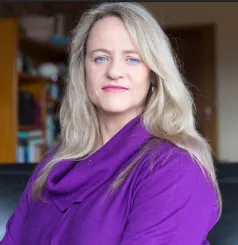 Photo of the educator smiling warmly in a cozy, kid-friendly workspace
