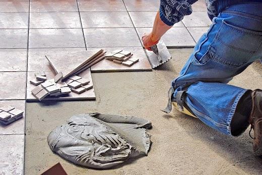 tile installation - contrator puts on new tiles on bathroom floor