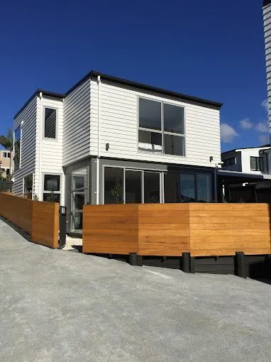 Modern two-storey residential home with a sleek white and grey exterior and timber fencing, representing new home construction.