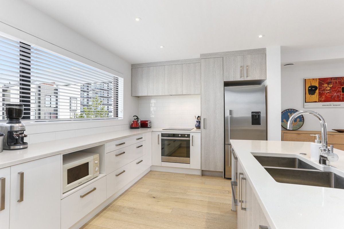 Modern kitchen with a wooden dining set, island bench, and pendant lighting, reflecting a clean and functional remodel.