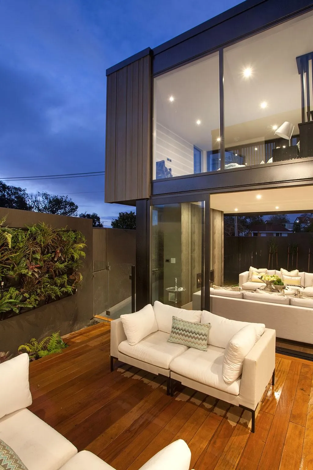 Contemporary open-plan living space with warm lighting and glass walls, showcasing stylish interior renovations.