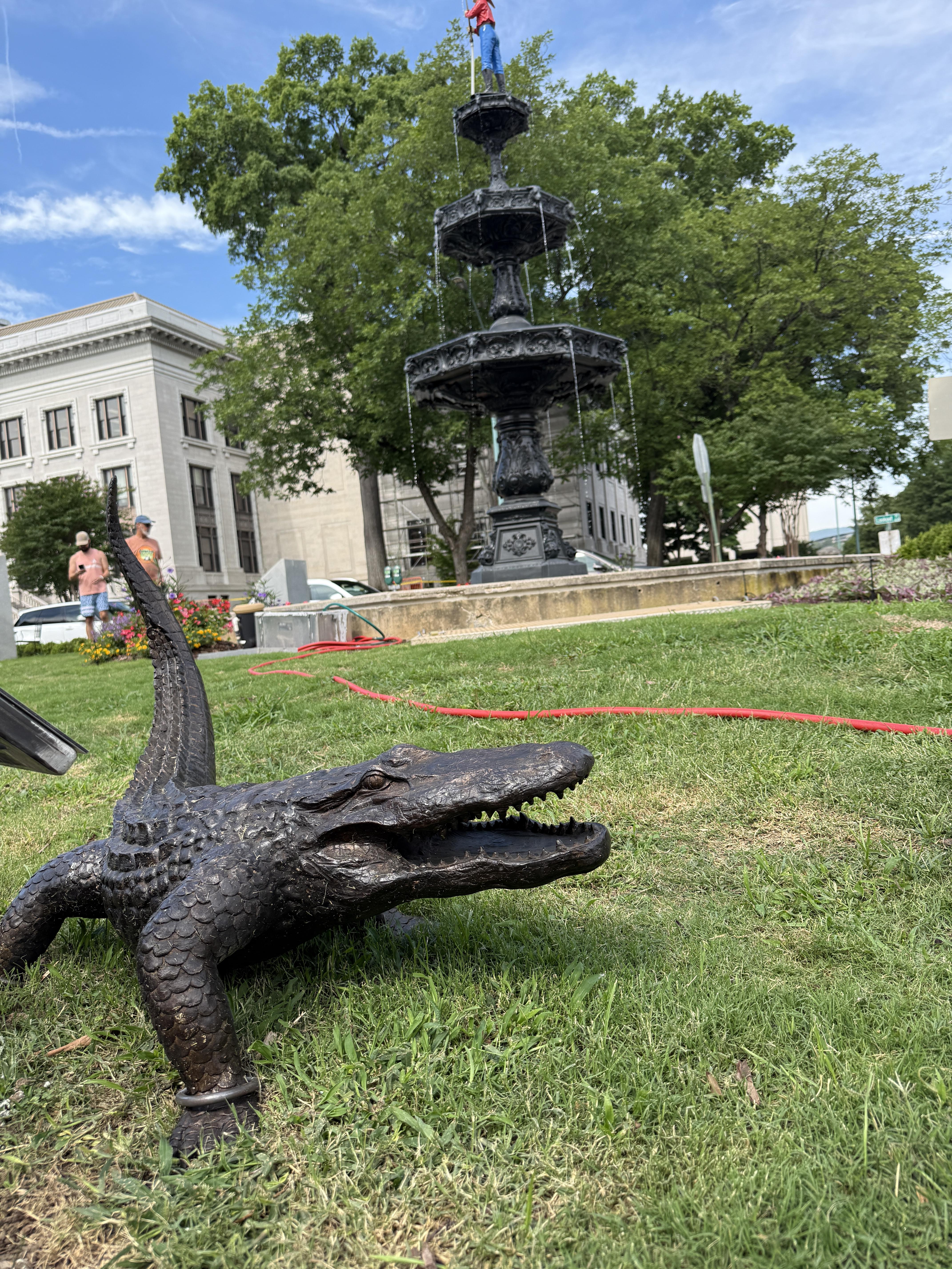 Bronze alligator sculpture in Fountain Square with Fireman's Memorial Fountain in downtown Chattanooga, Tennessee.