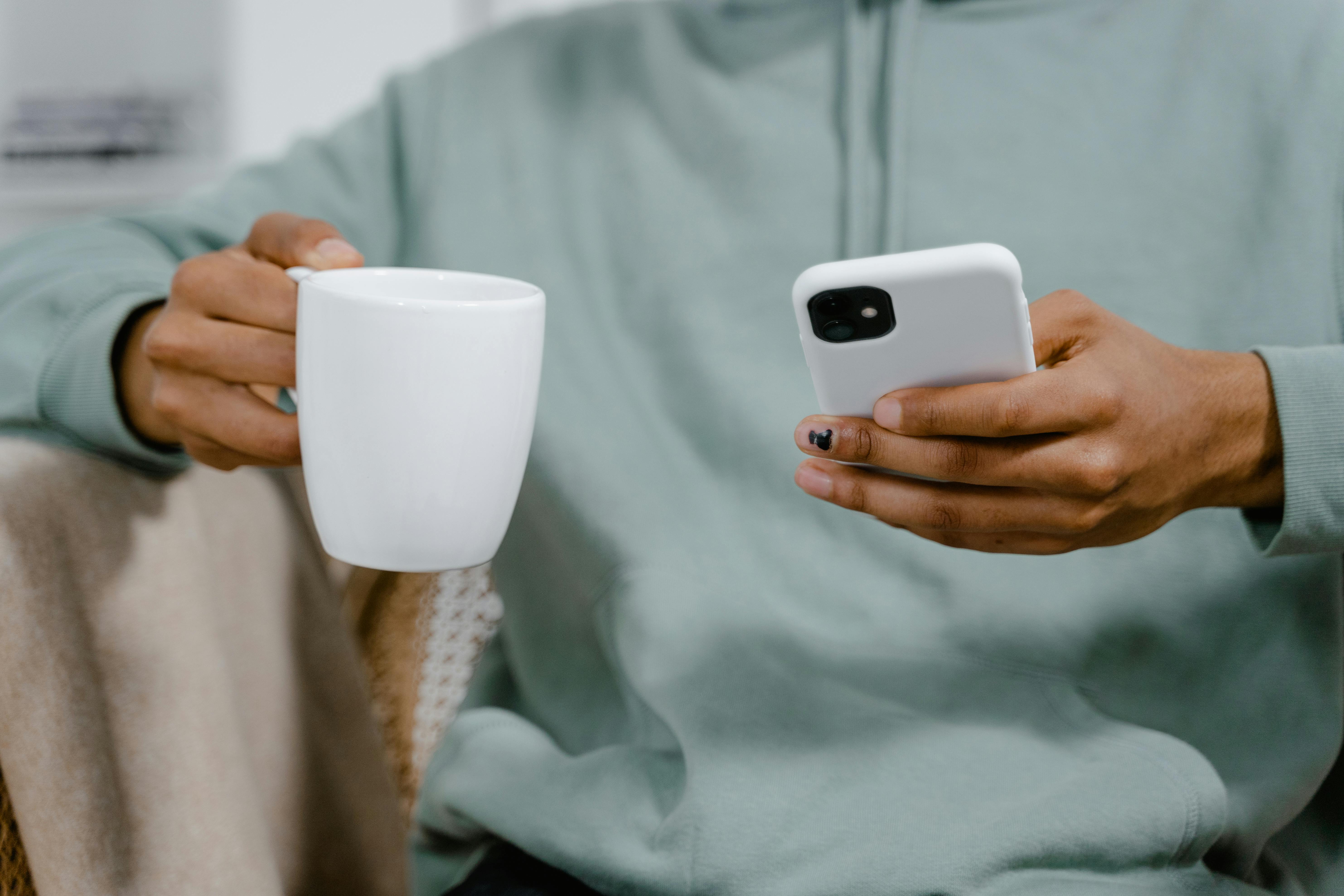 Hands holding a phone and coffee, symbolizing reflection and taking small steps toward clarity