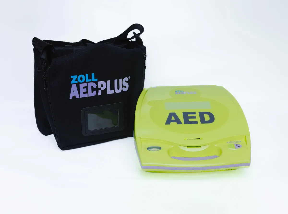 Zoll AED Plus closed with black carrying bag standing behind it