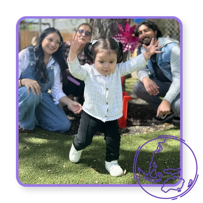 Smiling toddler enjoying outdoor learning with supportive adults at Blossoming Humans Preschool.