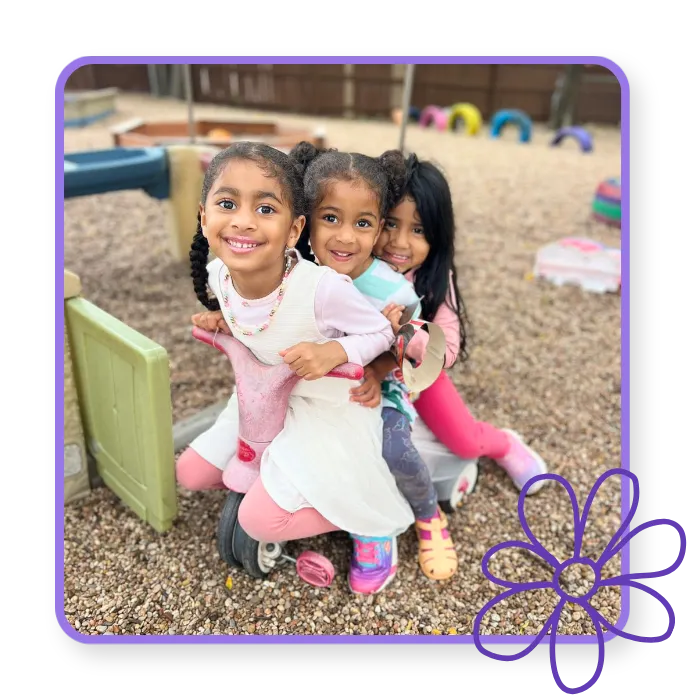 Three smiling children playing together outdoors at Blossoming Humans Spanish immersion preschool in Austin, Texas.