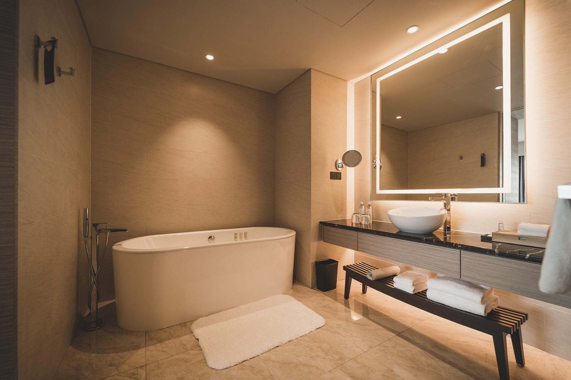 beige bathroom with bathtub, LED mirror and basin