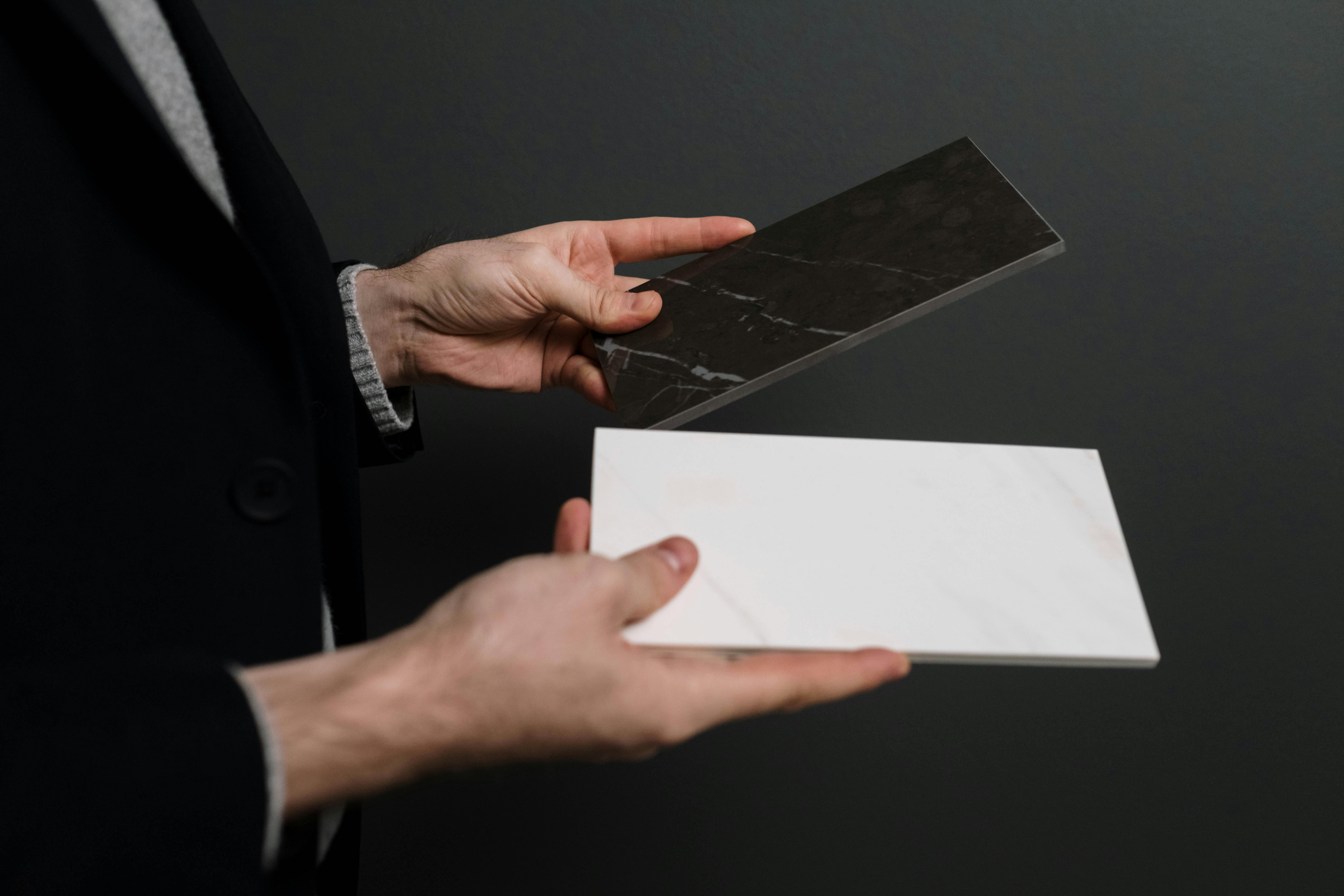 hands holding white and black tiles