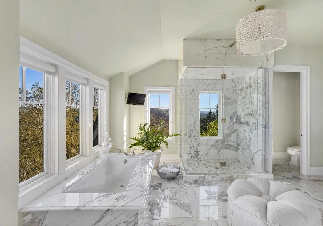 white marbly bathroom with a tub, large shower, and seating cushion