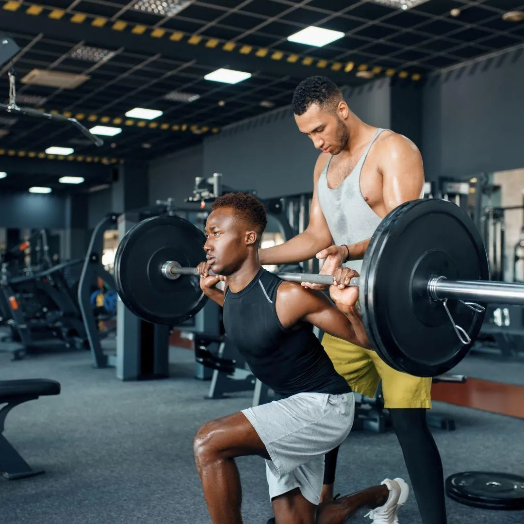 Trainer Helping Athlete on the Gym