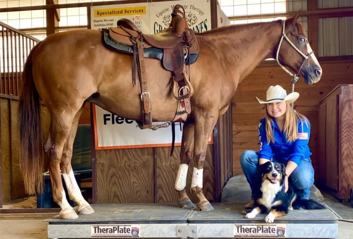 A lady with her horse and dog resting on the TheraPlate