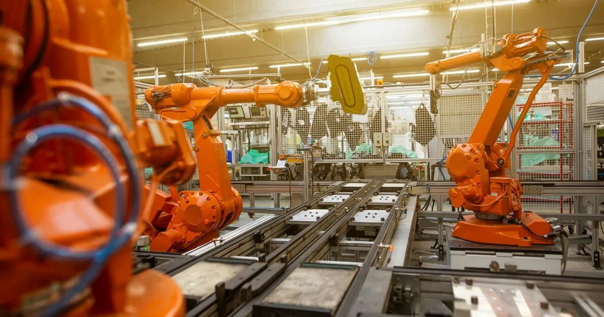 Orange robotic arms working along a factory line, a plain picture of automation doing repeat work