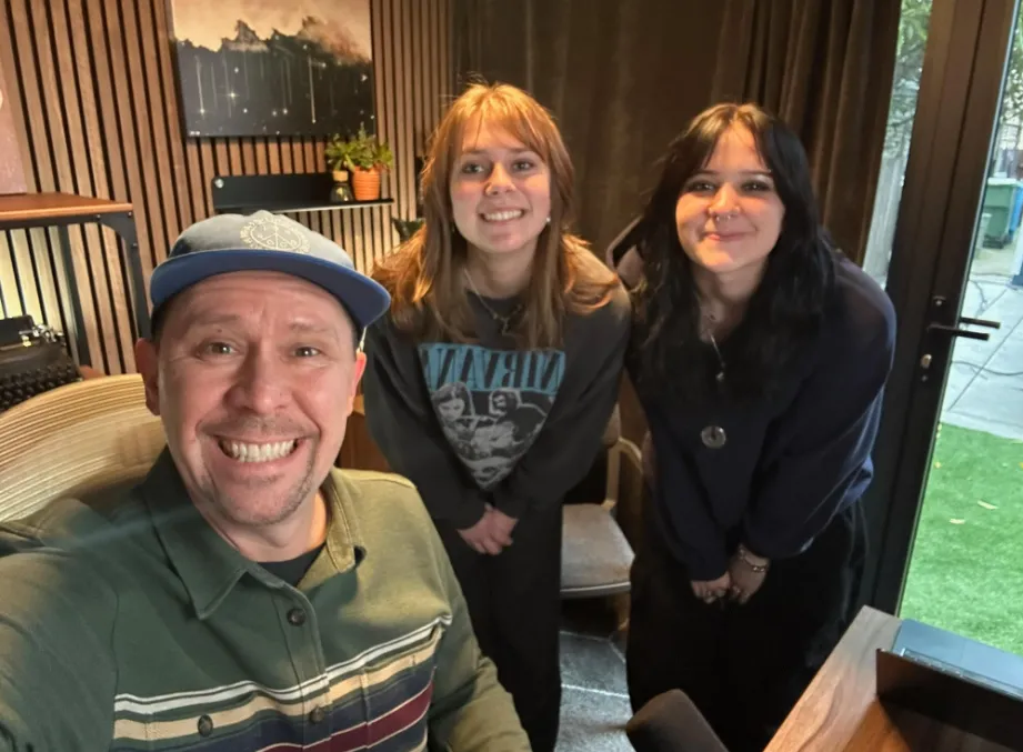 Production desk with laptop, notes, coffee, and microphone in moody lighting.