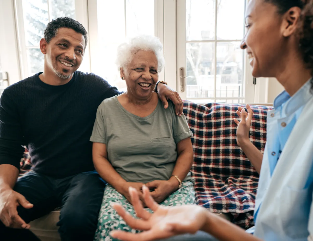 woman holding a cup of coffee at right hand and reading book on her lap while holding it open with her left hand in a well-lit room