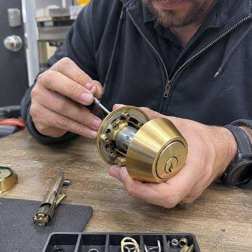 close up picture of a locksmith repairing a brass deadbolt lock in dallas, ga