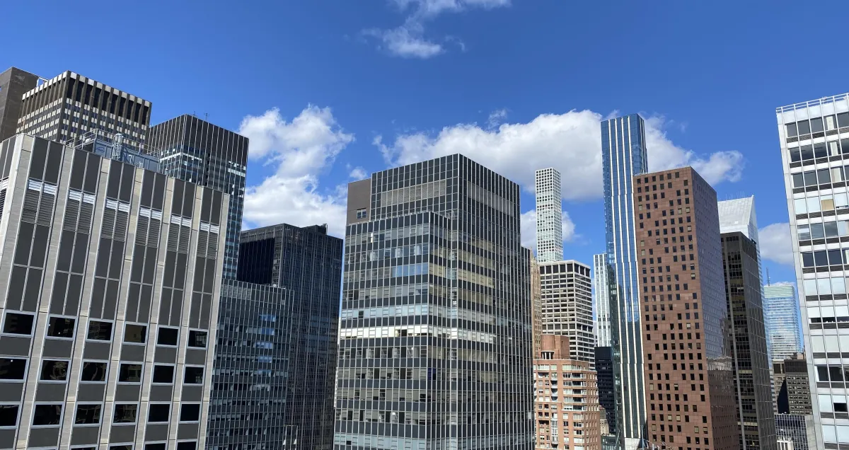 A close-up of hands sketching user journey maps on paper, surrounded by sticky notes and digital devices, emphasizing empathy and thoughtful planning in a creative workspace.