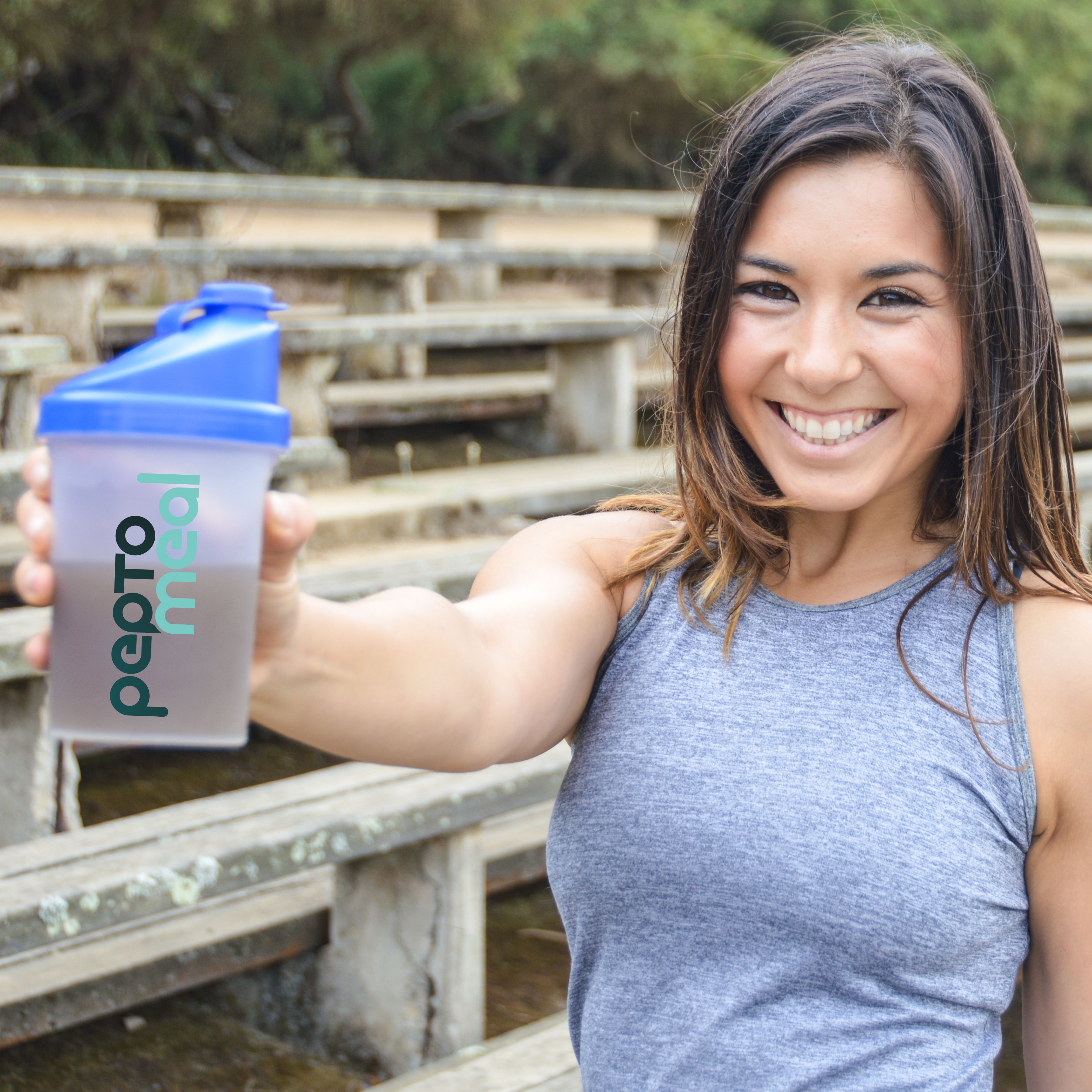 Smiling professional sipping VitaShake at a cafe table, shallow depth-of-field (1:1).