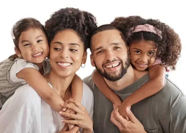 A happy family of four standing together, smiling warmly at the camera