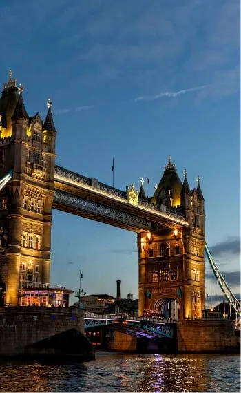 Vue nocturne de la Tour de Londres et du Tower Bridge, illuminés au bord de la Tamise, capturant la beauté iconique de la ville de Londres.