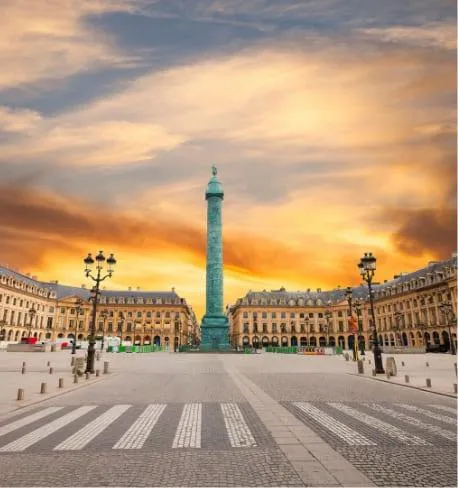Place Vendôme à Paris, vue sur la Colonne Vendôme sous un ciel doré au coucher du soleil, illustrant l'élégance historique et l'architecture classique de la capitale française.