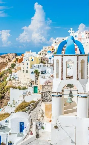 Vue pittoresque de Santorin, Grèce, avec ses maisons blanches caractéristiques et son église à dôme bleu, surplombant la mer Égée sous un ciel ensoleillé.