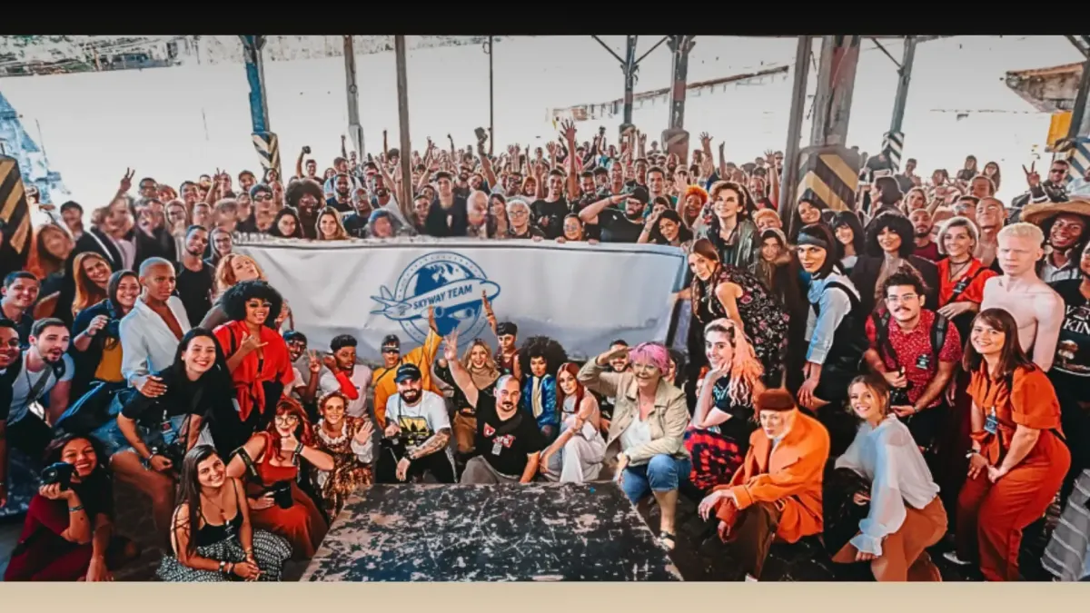 Großes Gruppenfoto des Skyway Teams bei einer internationalen Veranstaltung, mit einem Banner mit dem Team-Logo und lächelnden Teilnehmern aus aller Welt.