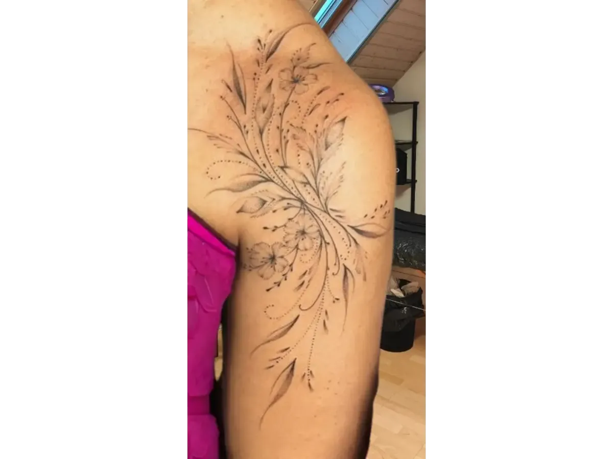 Tatouage floral délicat sur l’épaule d’une femme, motifs de fleurs et feuillages en dotwork et lignes fines – Magic Tattoo Ink