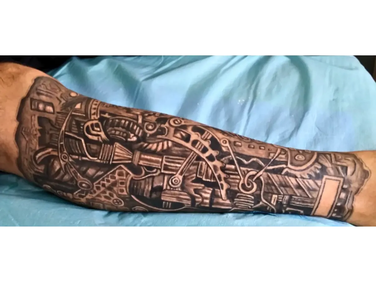 Tatouage biomécanique en noir et gris sur l’avant-bras, détails réalistes de rouages et engrenages – Magic Tattoo Ink