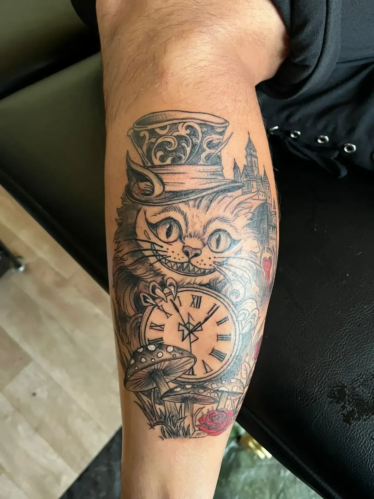 Tatouage inspiré d’Alice au pays des merveilles avec le chat du Cheshire, une horloge, des champignons et une rose – Magic Tattoo Ink