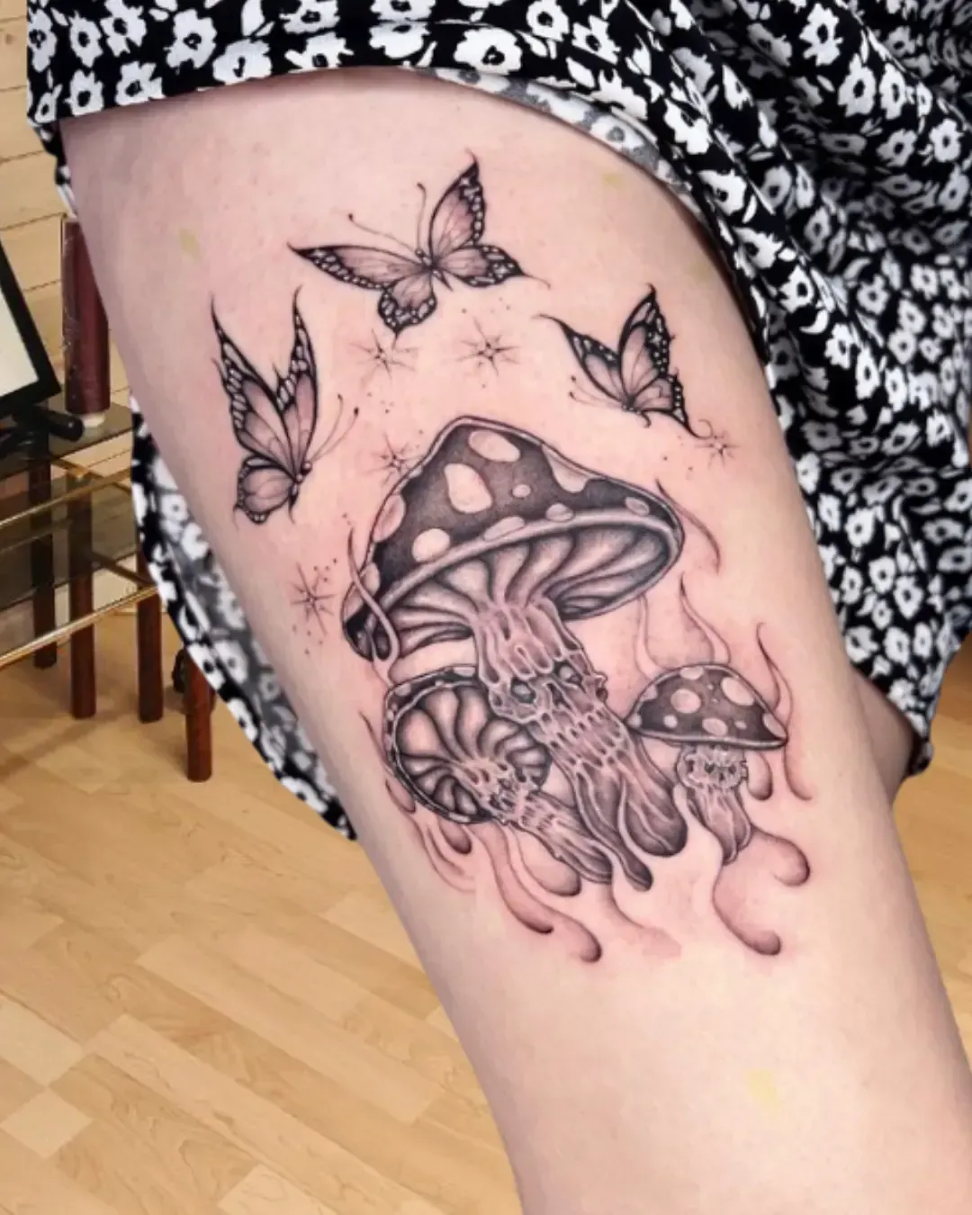 Tatouage artistique de champignons psychédéliques avec crânes intégrés et papillons – design onirique et symbolique, réalisé par Magic Ink à Fribourg.