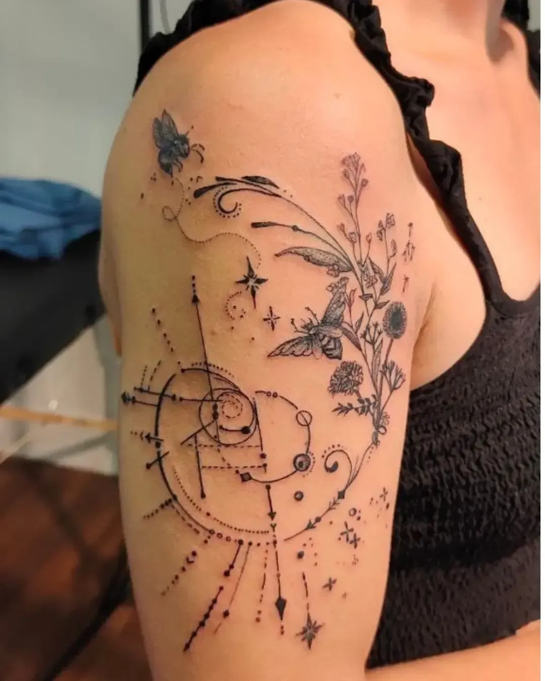 Tatouage ornemental sur le bras avec abeilles, fleurs sauvages et motifs géométriques – symbole de nature, harmonie et énergie cosmique, réalisé par Magic Ink à Fribourg.
