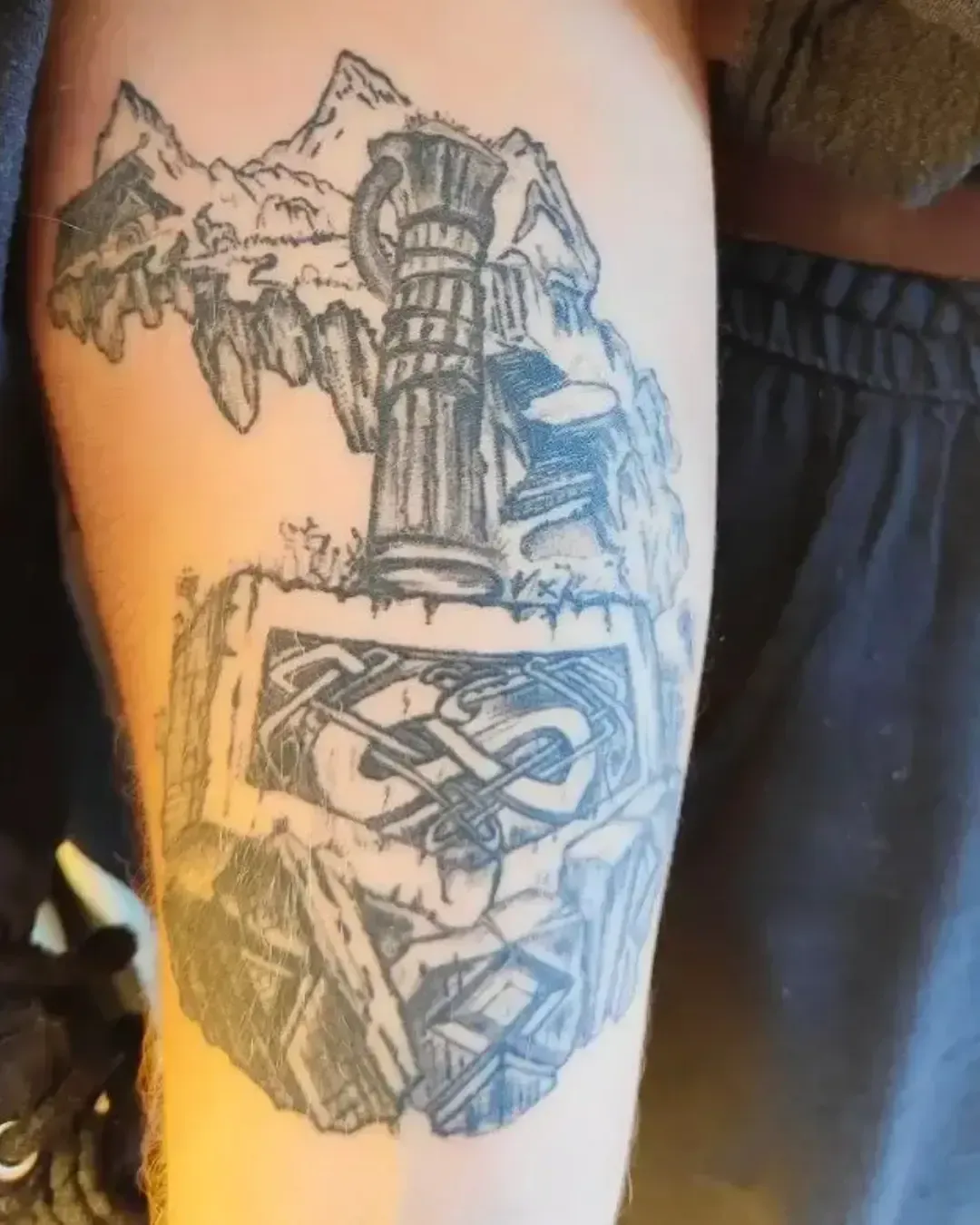 Tatouage marteau de Thor avec motifs nordiques et montagnes, symbole de puissance et protection viking – photo réalisée sur tatouage cicatrisé par Magic Ink à Fribourg.